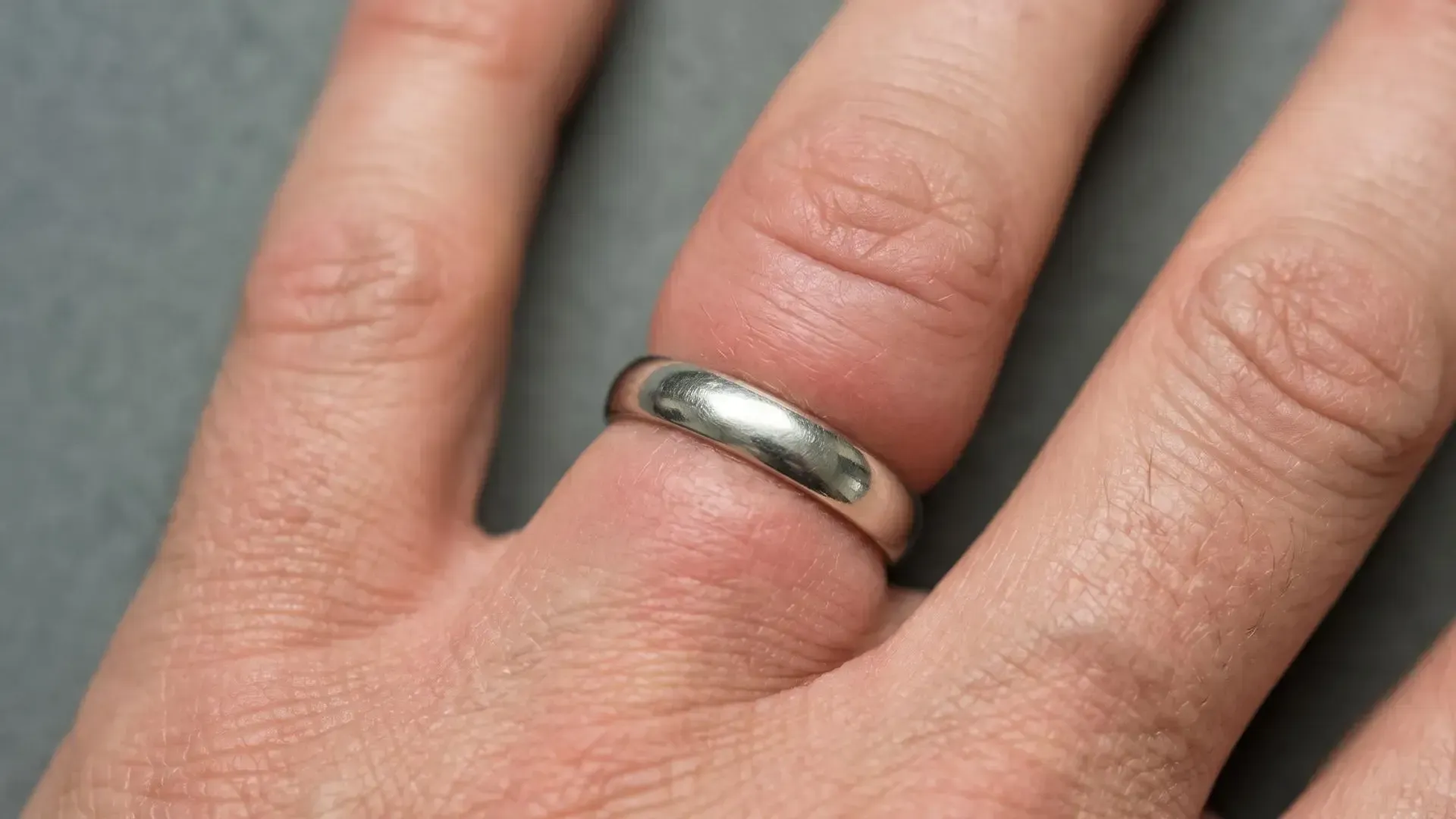 Close-up of a hand wearing a silver ring on a finger.