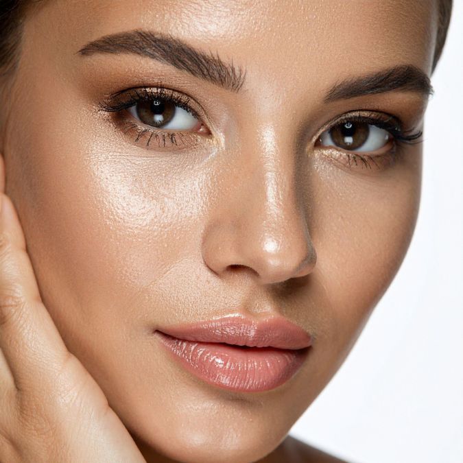 Woman with radiant skin, wearing subtle makeup, looking at the viewer.