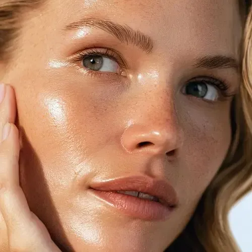 Woman with radiant, glossy skin, hand on cheek, looking upward.