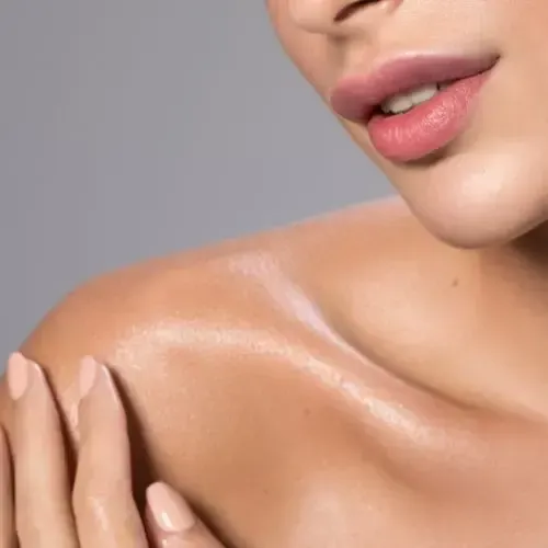 Close-up of a person's shoulder and lips with a healthy glow. Light skin tone, pink lips, soft lighting.