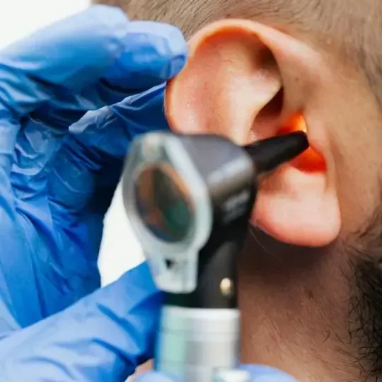 A doctor is examining a patient 's ear with an otoscope.