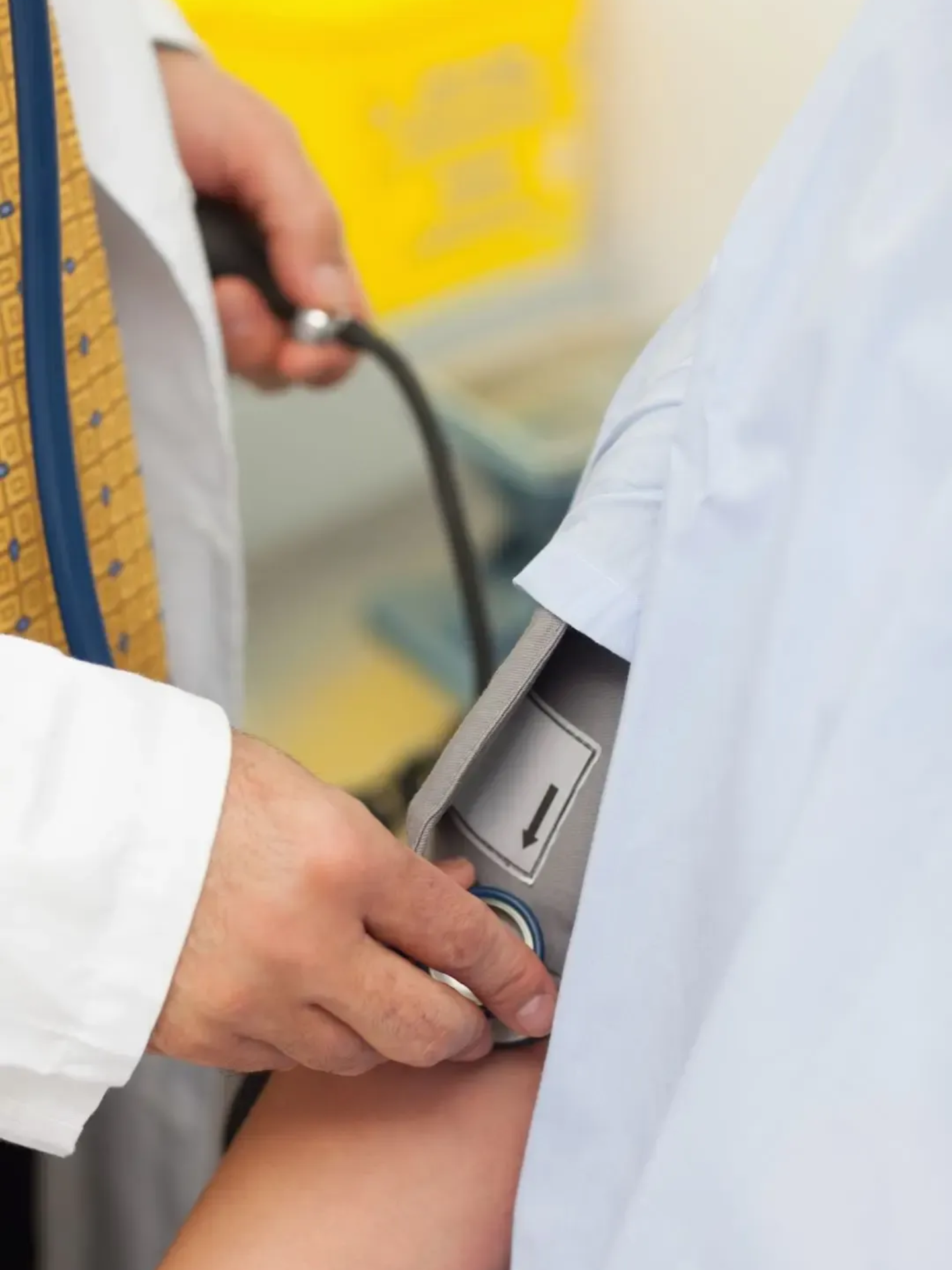 Doctor taking a patient's blood pressure with a stethoscope and cuff on their arm.