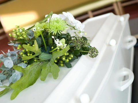 cofano funebre bianco con corona di fiori