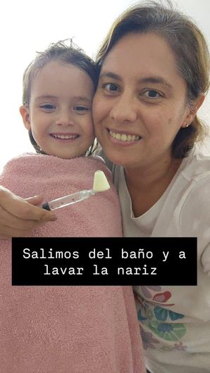 Mujer y niño sonriente en un baño, envueltos en toallas rosas; el pie de foto dice “Salimos del baño ya lavar la nariz”.
