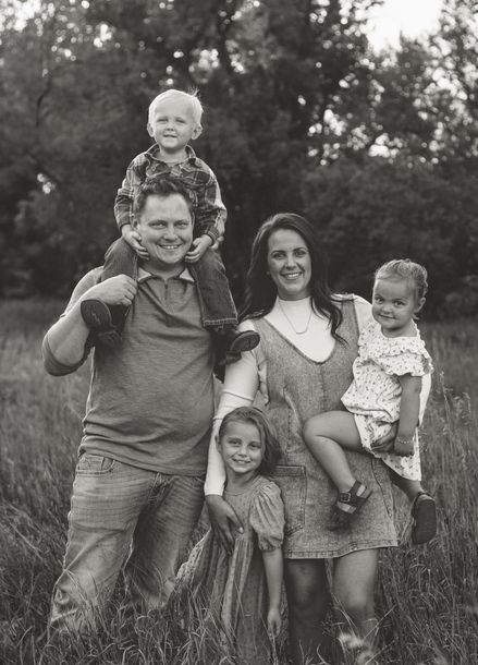 A black and white photo of a family posing for a picture in a field.