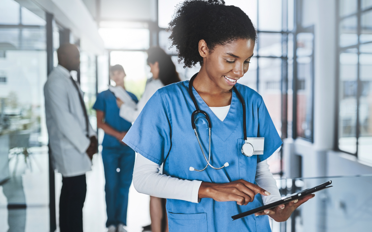 A nurse is using a tablet in a hospital hallway.