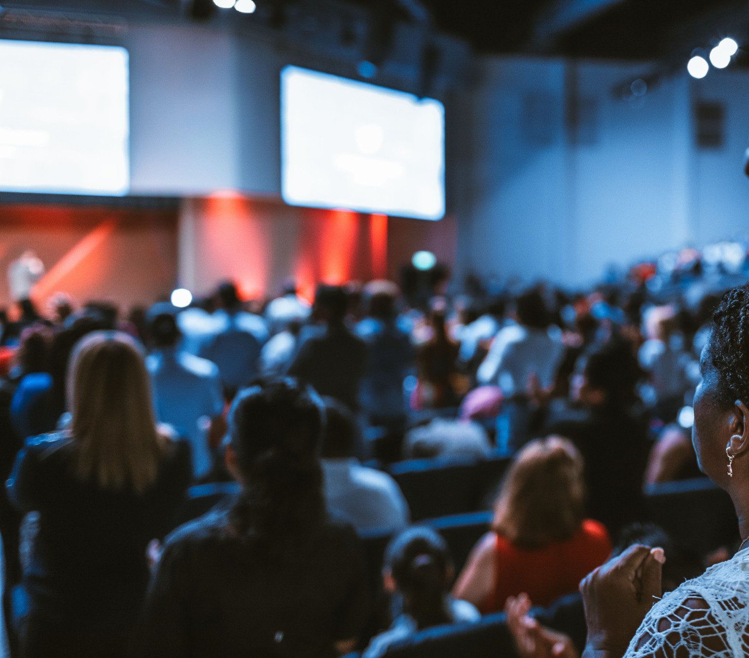 A woman is standing in front of a crowd of people at a conference.