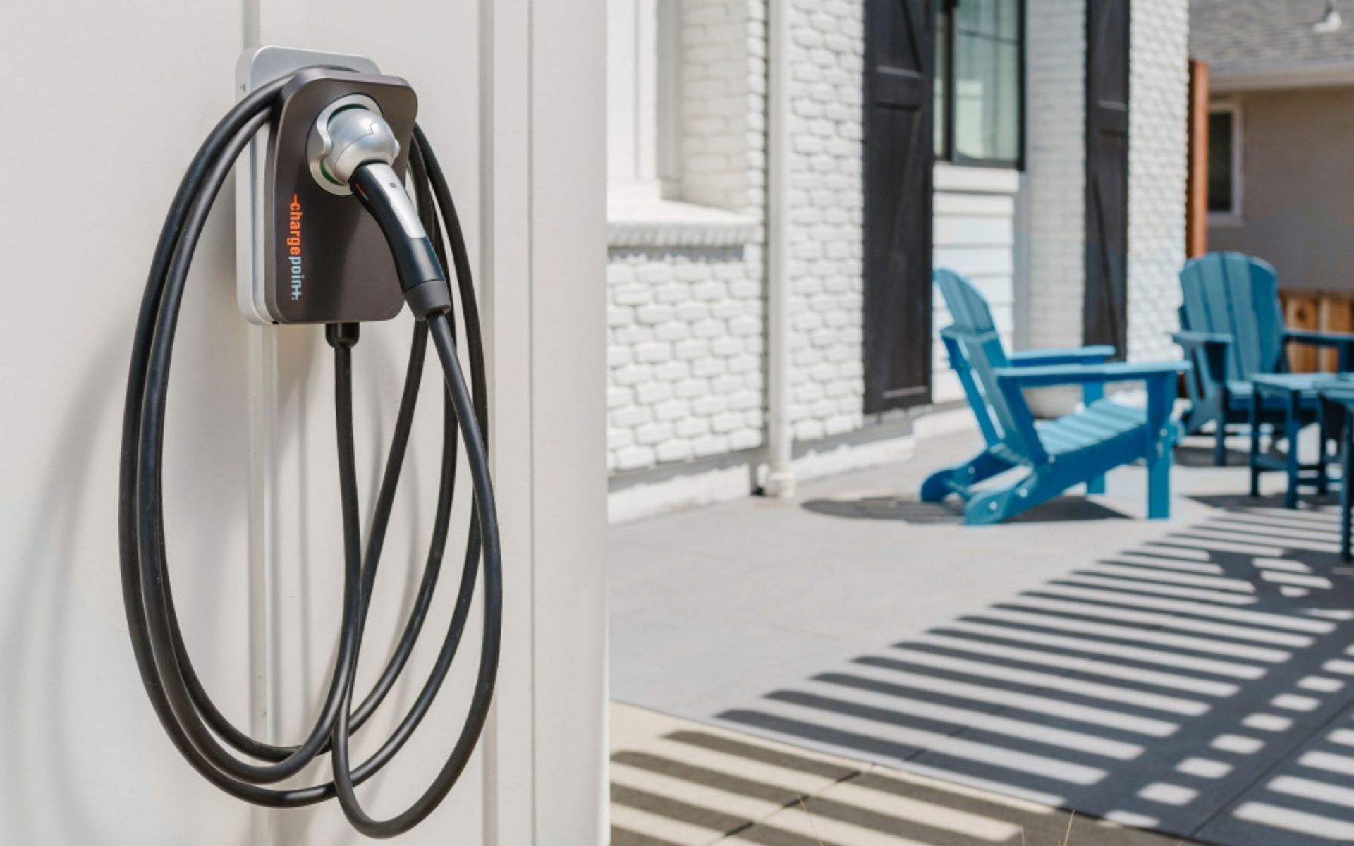 Blue electric car charging in a garage with charger mounted on the wall.