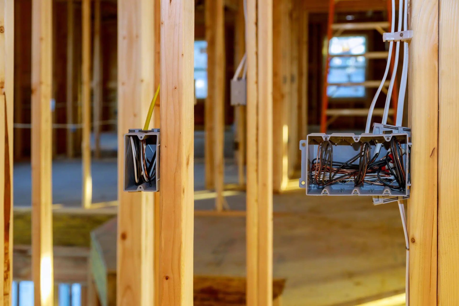 Wooden framing with exposed plumbing and electrical wiring in a building under construction.