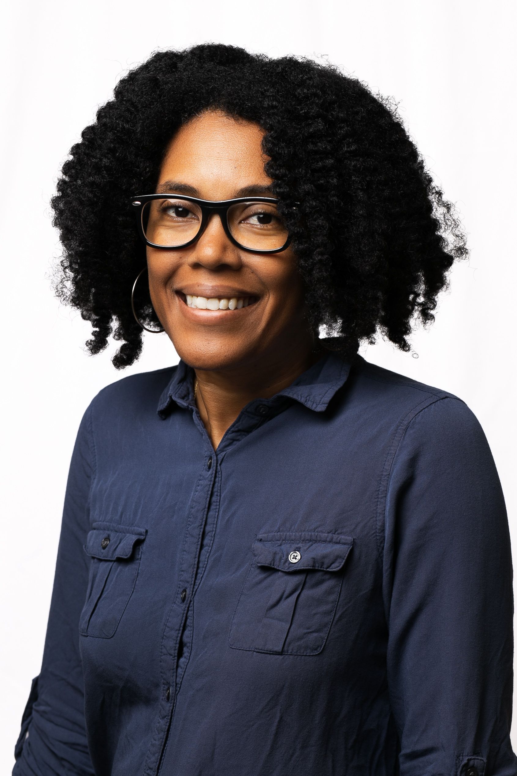 A woman with an afro and hoop earrings smiles for the camera