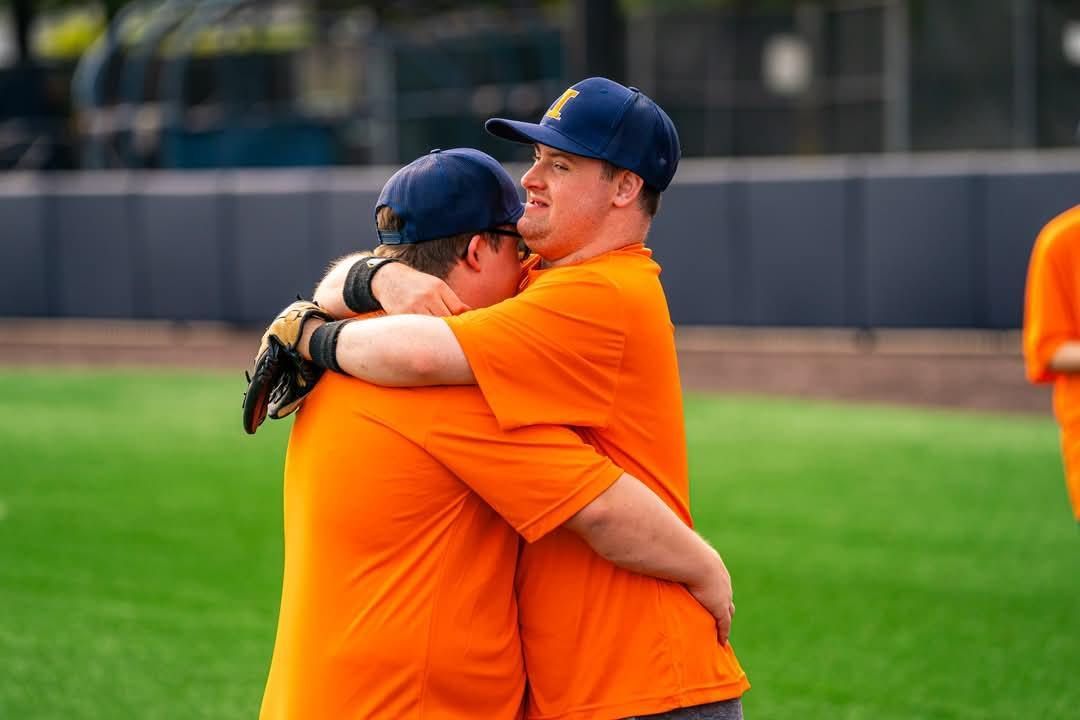 Two men are hugging each other on a baseball field.