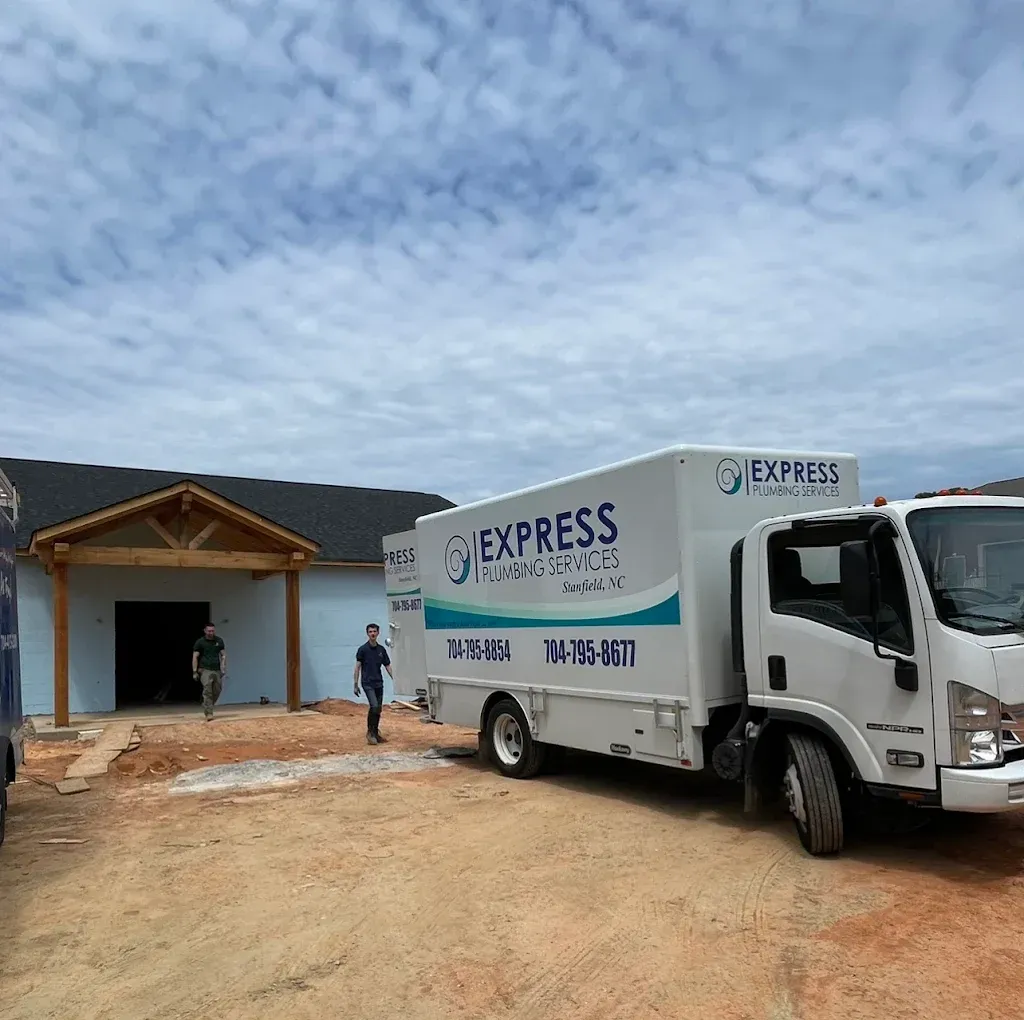 Express delivery truck parked in front of a building under construction; two men walk by.