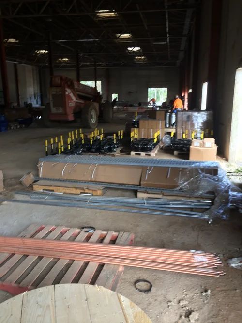 Inside a warehouse, construction materials are staged. Includes copper tubing, a forklift, and various boxes.