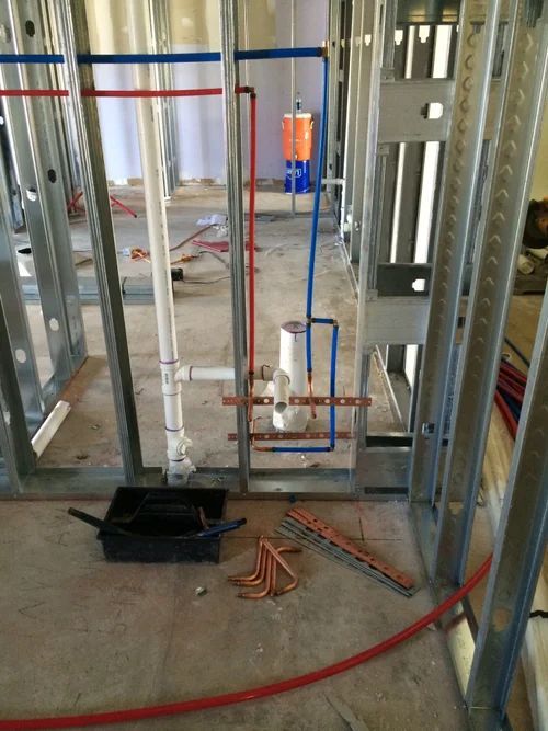 Plumbing rough-in for a shower with copper and PEX piping within metal framing.
