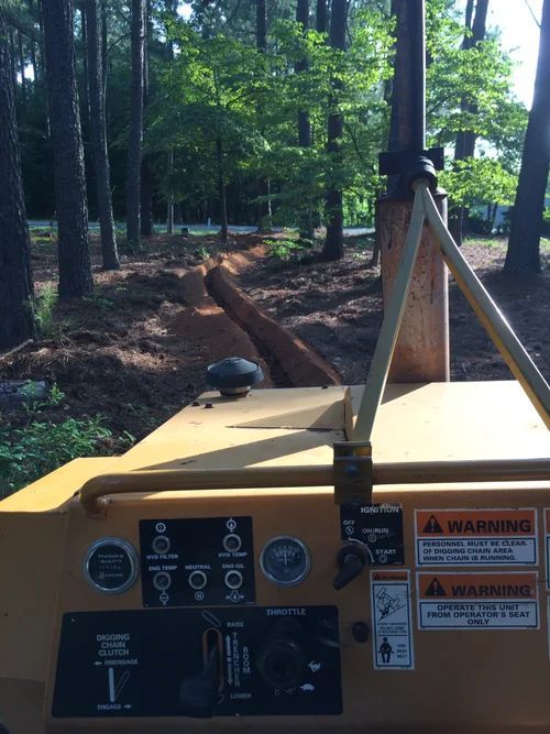 Yellow stump grinder grinding a tree stump in a wooded area.