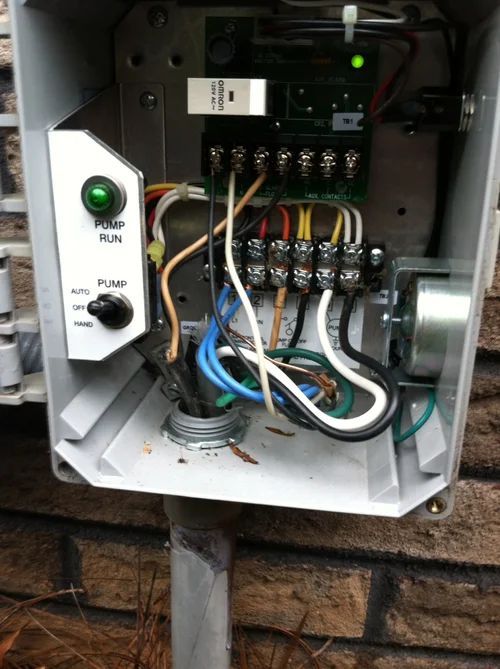 Open irrigation control box with wires connected to a terminal block, featuring a pump run switch.