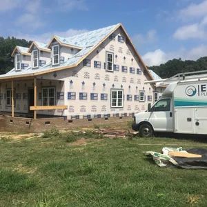 House under construction with a white service van parked nearby on a sunny day.