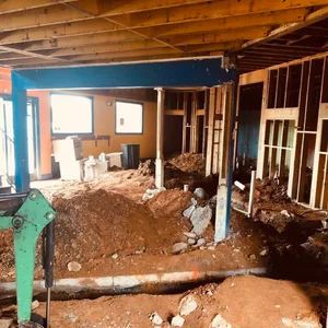 Construction site with dirt, wooden frames, and blue steel beam.