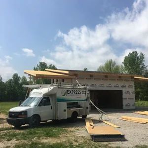 White van with Express Plumbing logo parked at a construction site; unfinished building, sunny day.