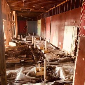 Construction site interior: exposed walls, plumbing, and debris.  Hallway with red and blue walls.