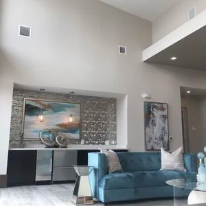 Modern living room with a blue sofa, artwork, and a bar area with mirrored cabinets.