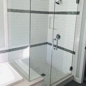 Glass shower with white subway tile walls and a dark gray tile band.