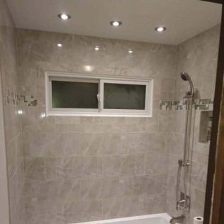 Bathroom with tiled walls, window, recessed lighting, and shower fixture.