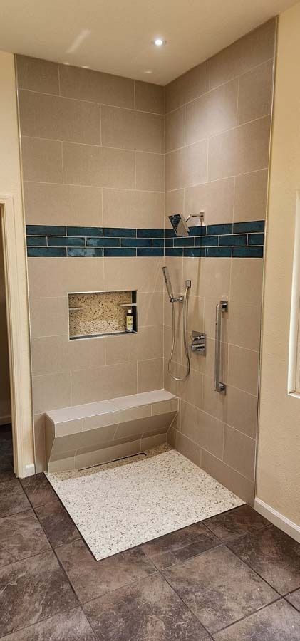 A tiled shower with a built-in bench, teal accent, and grab bar.
