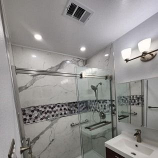 Modern bathroom with marble tile, glass shower, and vanity.