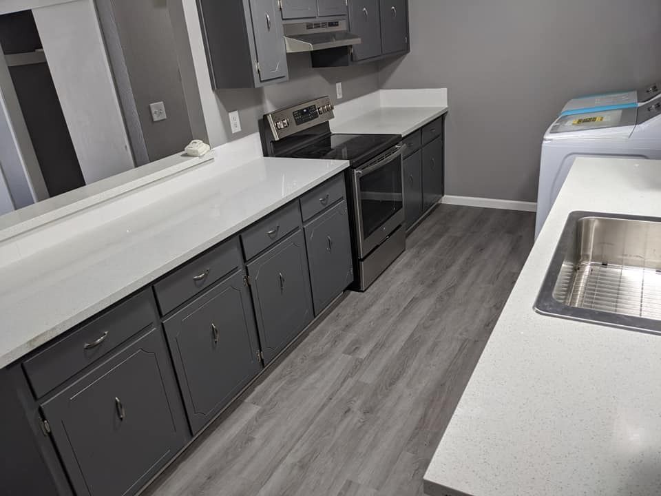 Gray kitchen with white countertops, stainless steel appliances, and washing machine.