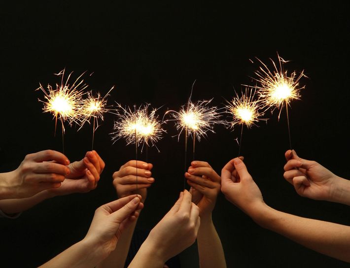 hands holding sparklers against black background