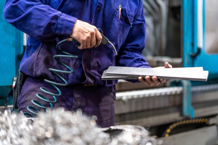 a man in a blue uniform is working on a machine and holding a clipboard .