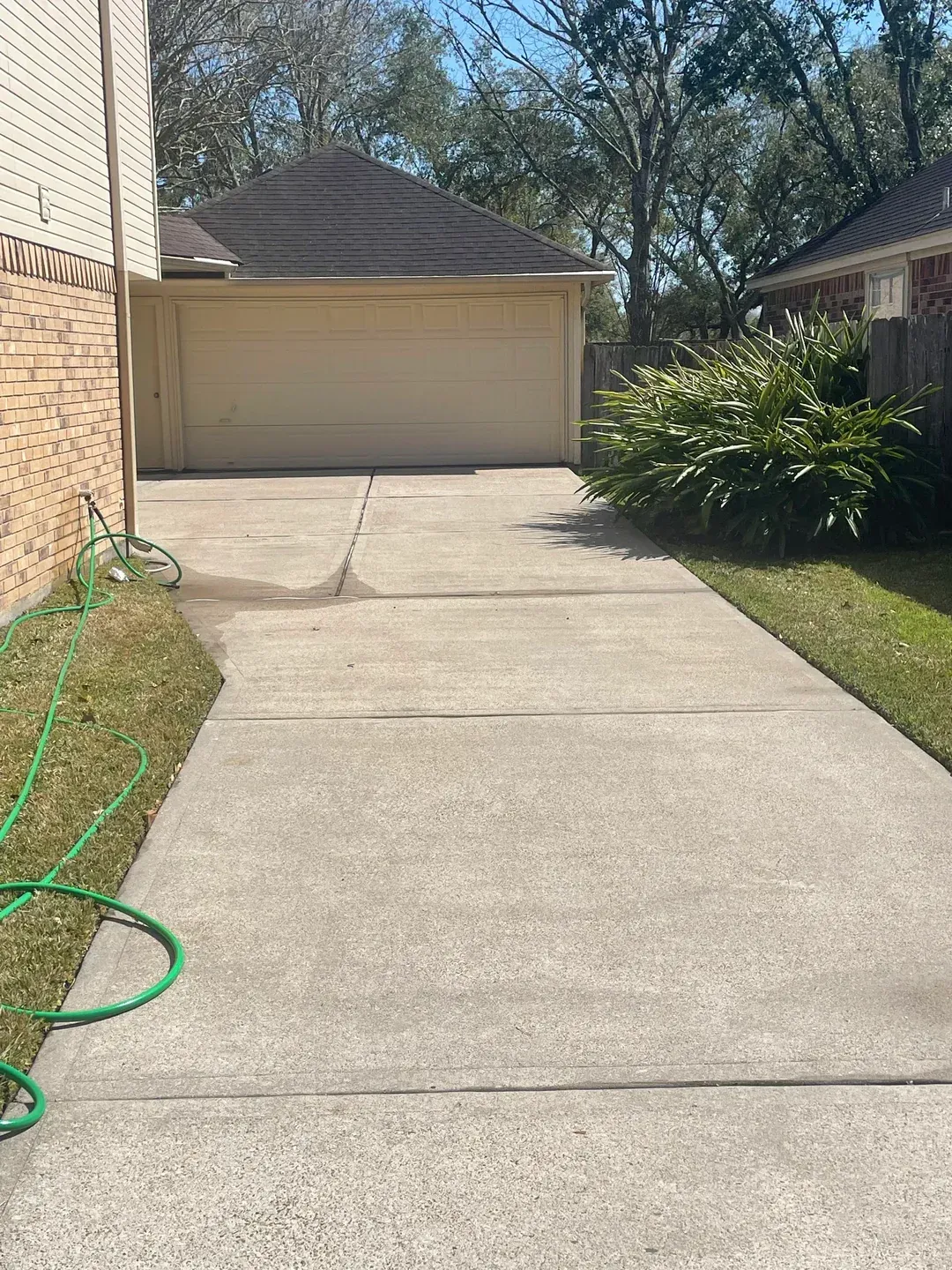 Concrete driveway leading to a two-car garage; green grass borders driveway.