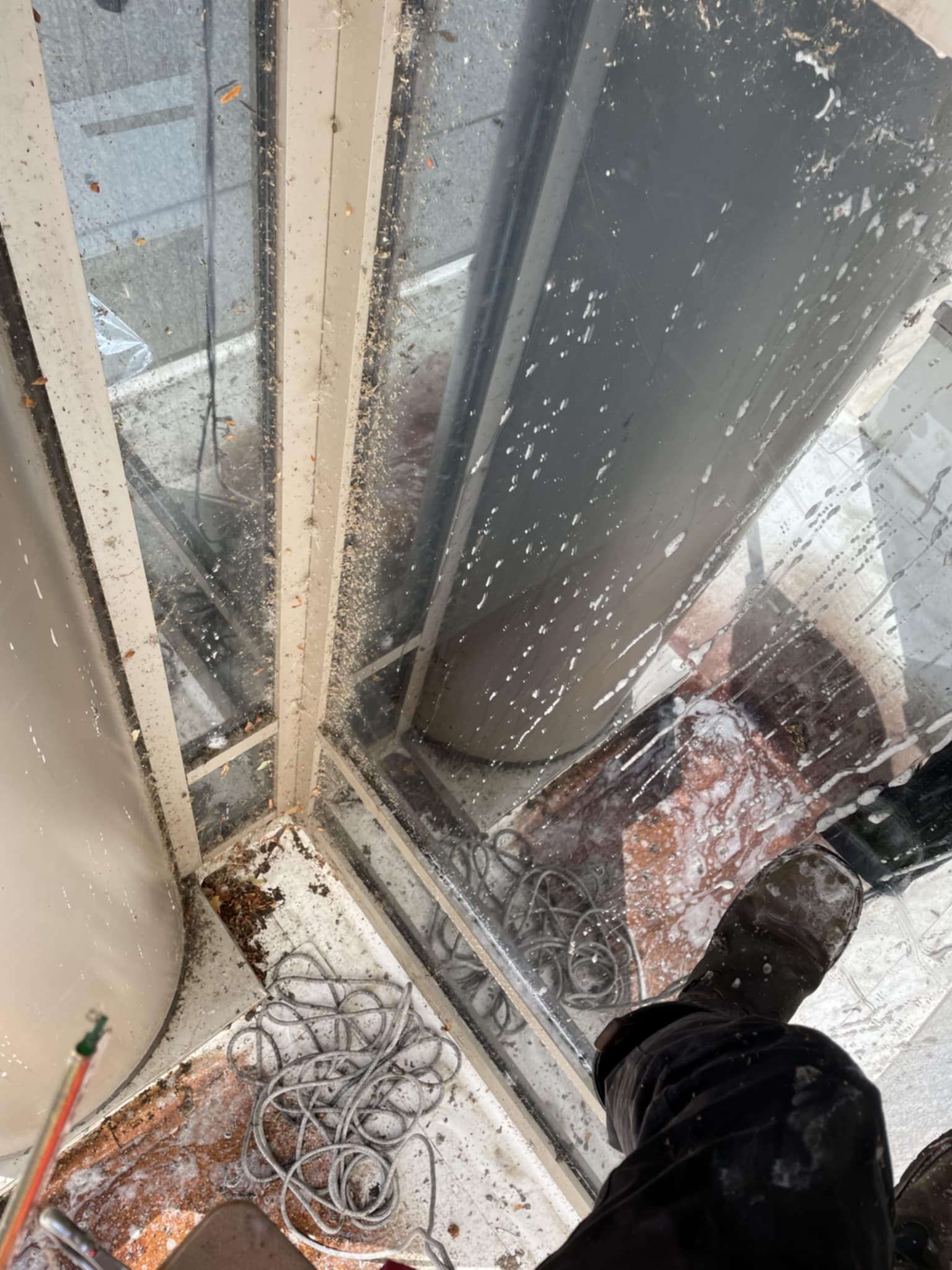 Looking up a corner of a building. White frame, glass, and a black pipe are visible. The angle is extreme.