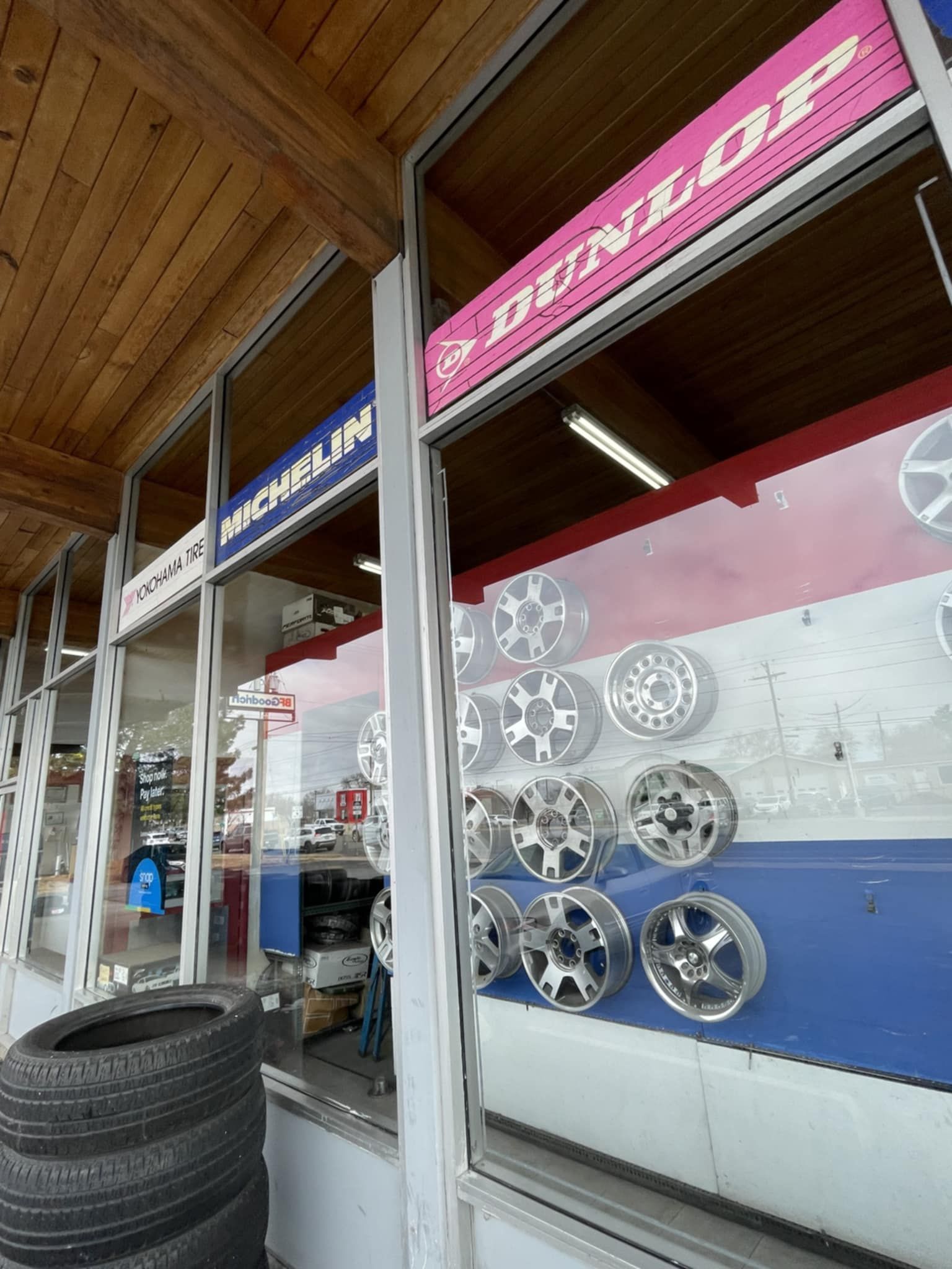 Tire shop display with stacked tires, tire rims, and signs for Dunlop and Michelin.