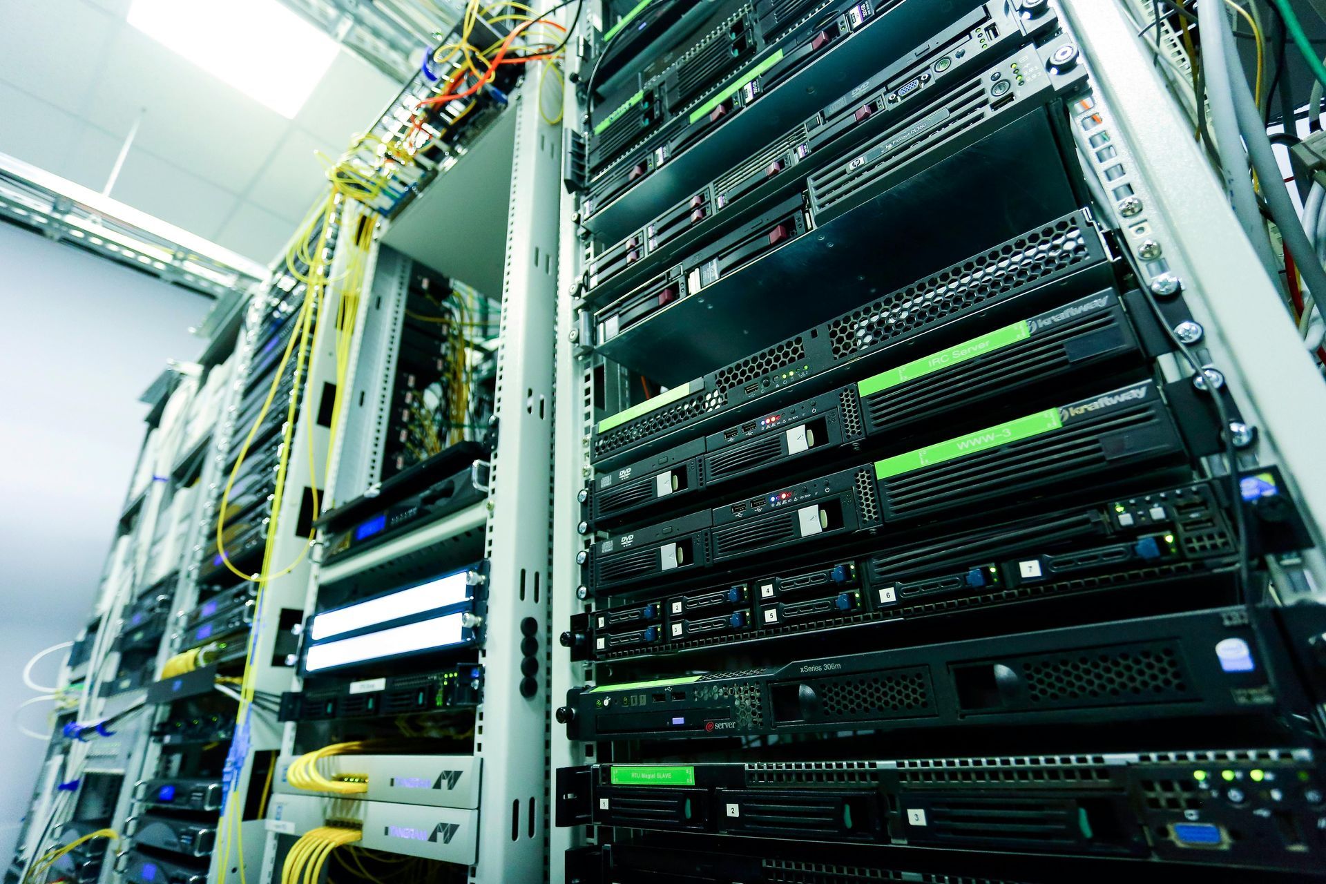A low-angle view of rows of server racks with flashing status lights and organized networking cables in a data center.