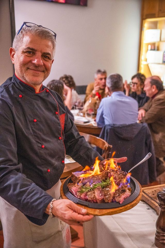 Tagliere di salumi e formaggi; le mani prendono una fetta.