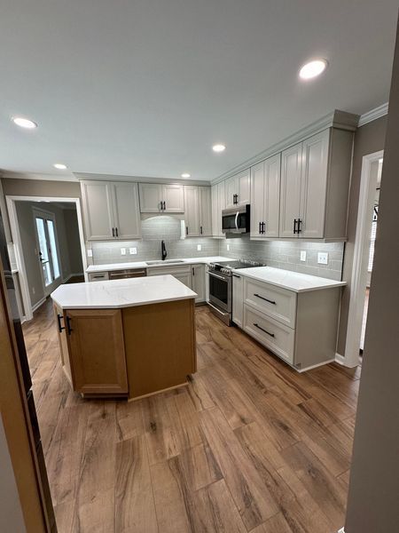 Modern kitchen with light gray cabinets, white countertops, and wood floors.