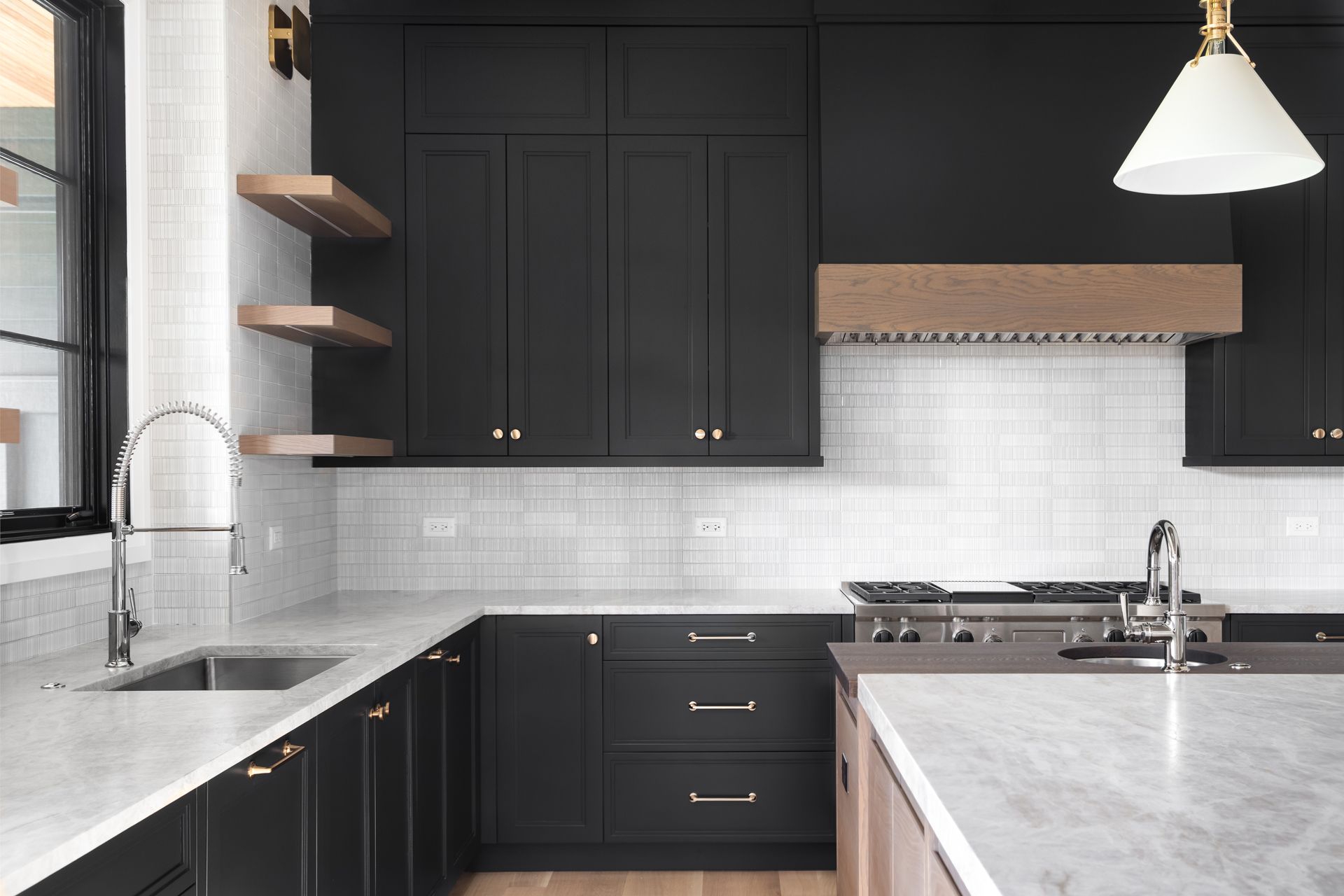 Modern kitchen with black cabinets, white countertops, and wooden shelves.