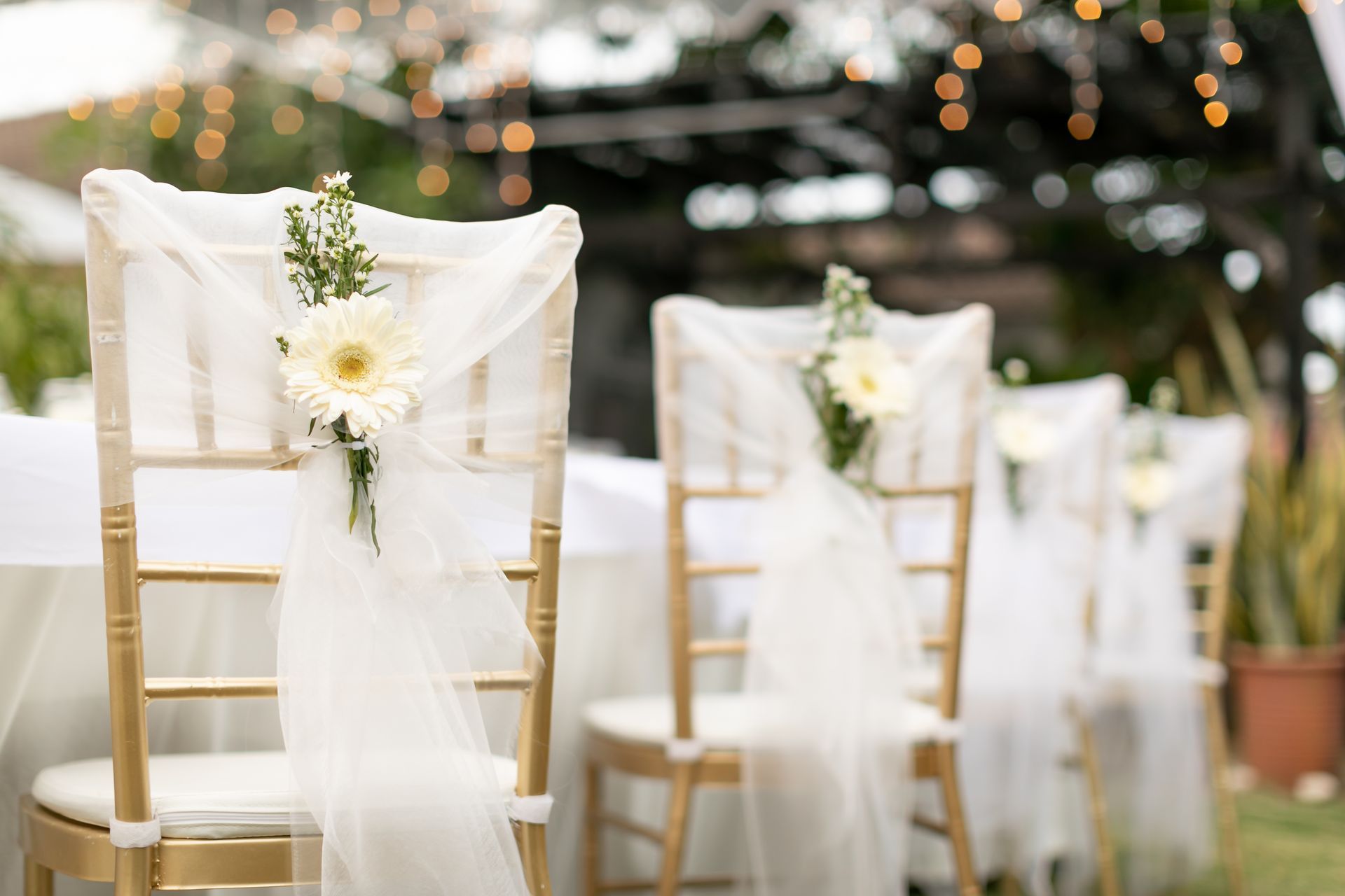 Golden chairs with white fabric and flowers