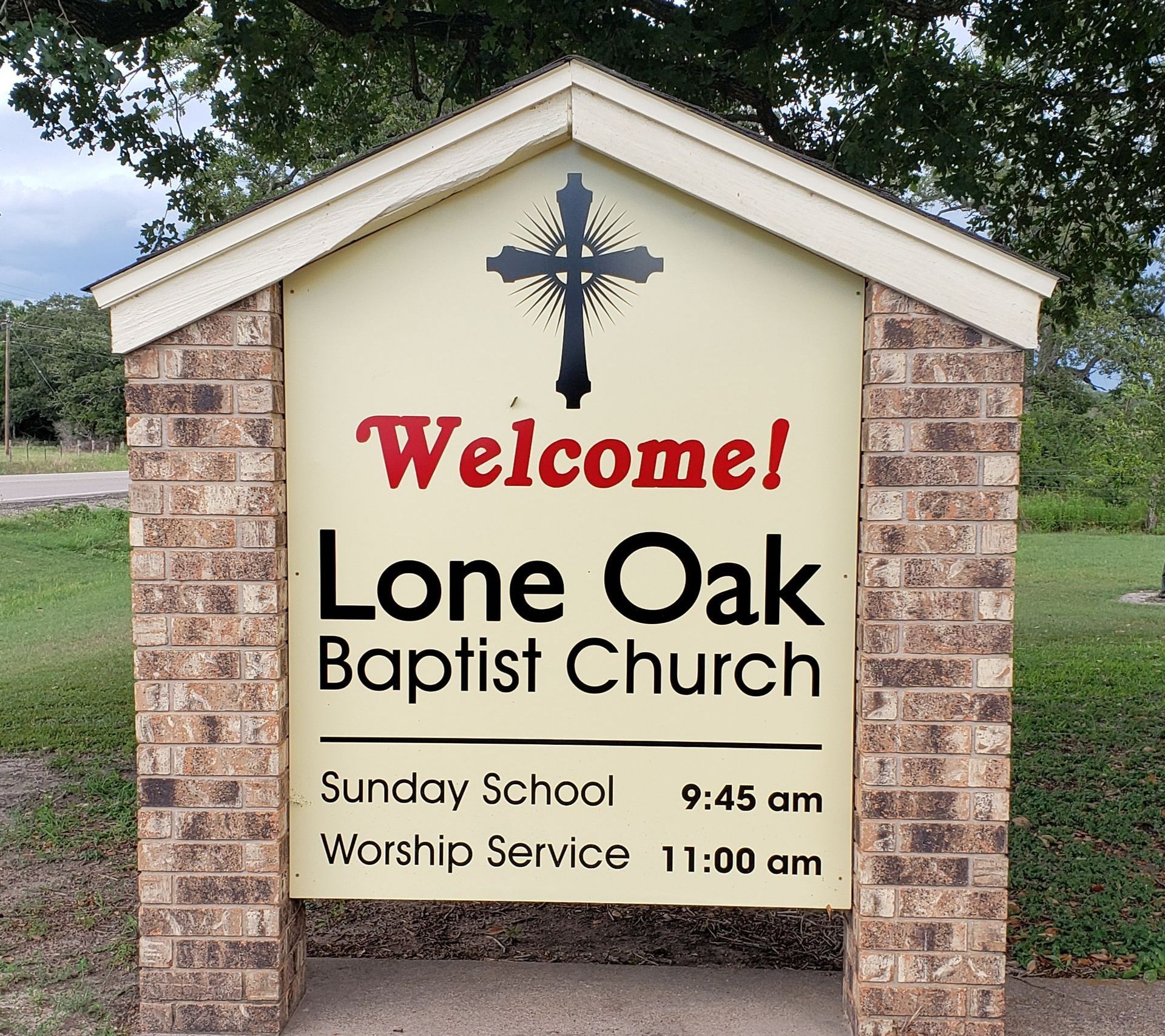 Sign for Lone Oak Baptist Church, with a cross, welcoming message, and service times.