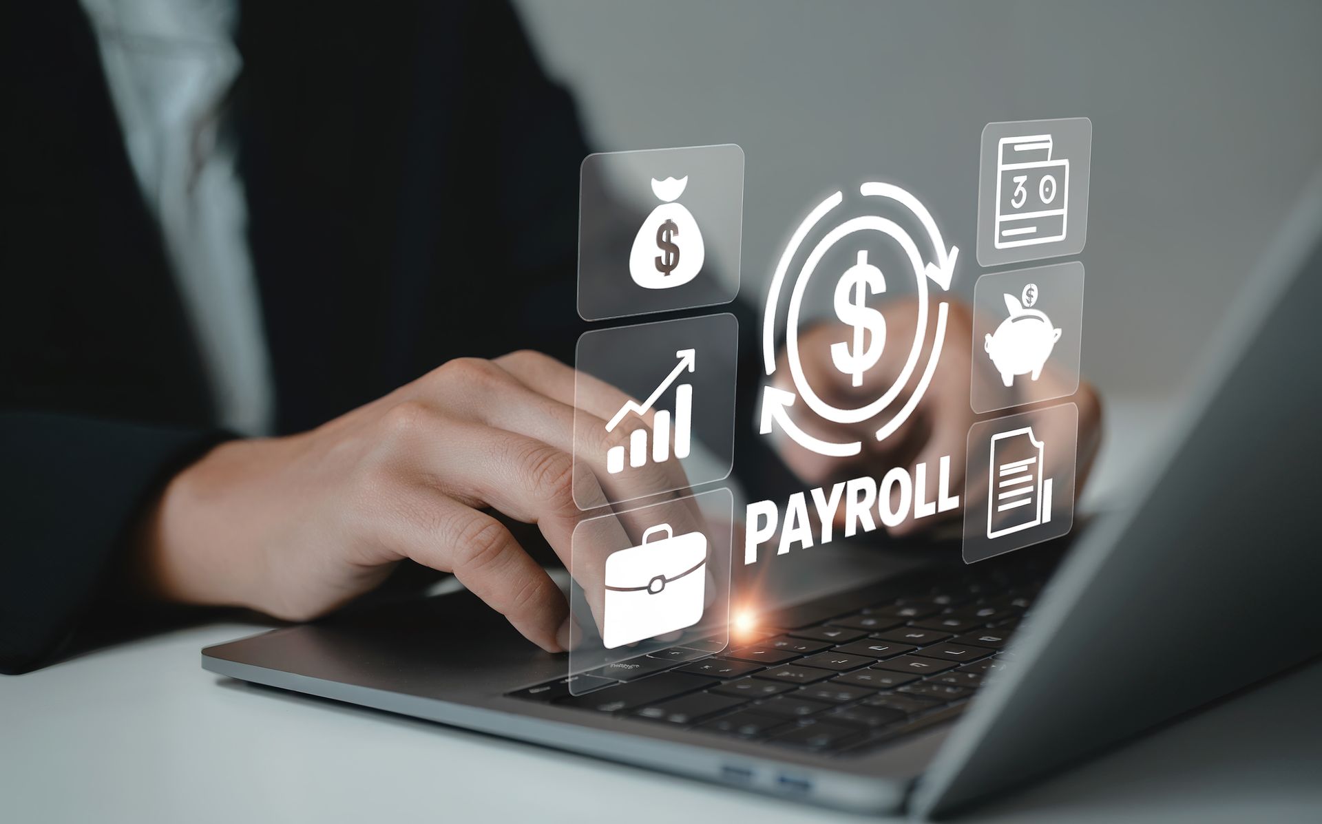 Hands typing on a laptop with payroll and finance icons glowing above the keyboard Hands typing on a laptop with payroll and finance icons glowing above the keyboard