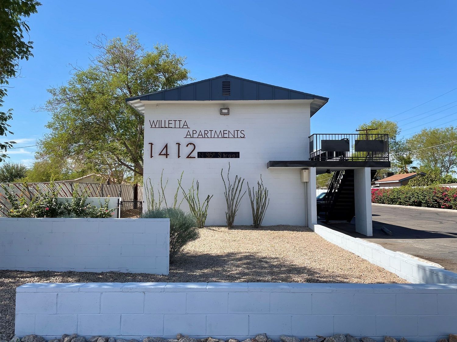White Marietta Apartments building at 1412, with a small balcony and gravel landscaping on a sunny day.