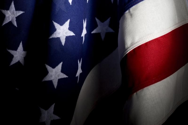 Close-up of the American flag with stars, stripes, and deep shadows.