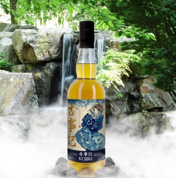 A bottle of kojiki sits in front of a waterfall