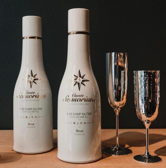 Two bottles of champagne are on a table next to champagne glasses