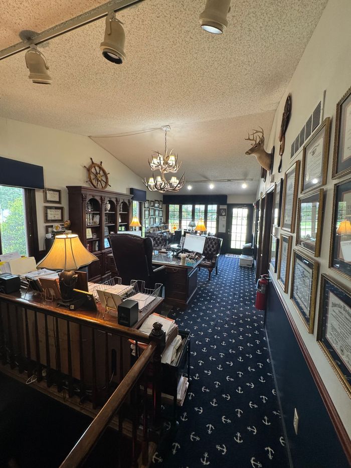 A room with a desk and a lamp and a few framed pictures on the wall