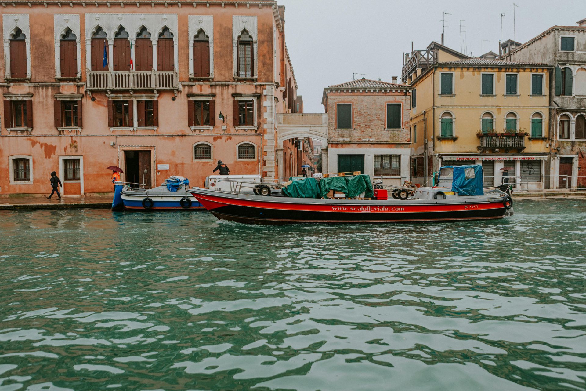 Venice canal scene: boats on water, colorful buildings along the banks.