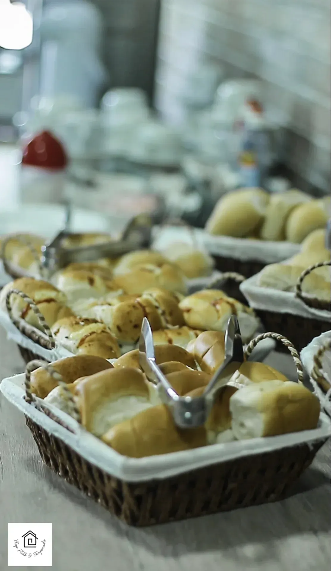 Uma fileira de cestos cheios de pão e pinças sobre uma mesa.