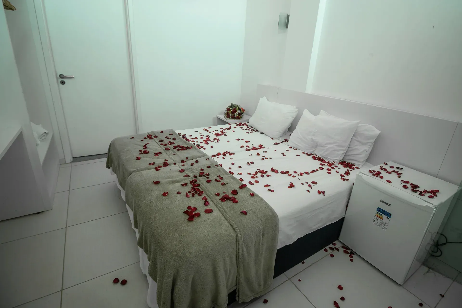 Um quarto de hotel com uma cama decorada com pétalas de rosa.